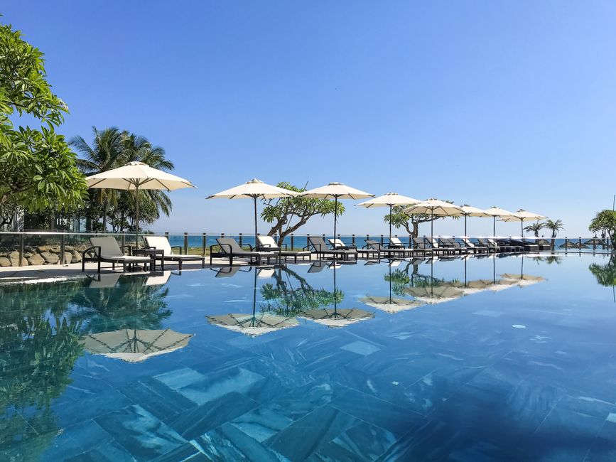 Stunning modern luxury villa in Los Cabos with a bright blue infinity pool that blends seamlessly into the ocean horizon u...