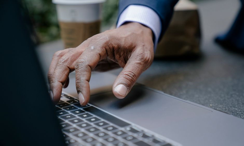 Close-up of a person in professional attire typing on a modern laptop, representing digital marketing and online client research for law firms.