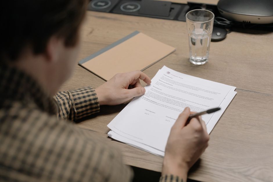 Close-up, professional photograph of a magnifying glass held over a real estate contract, emphasizing the scrutiny of lega...