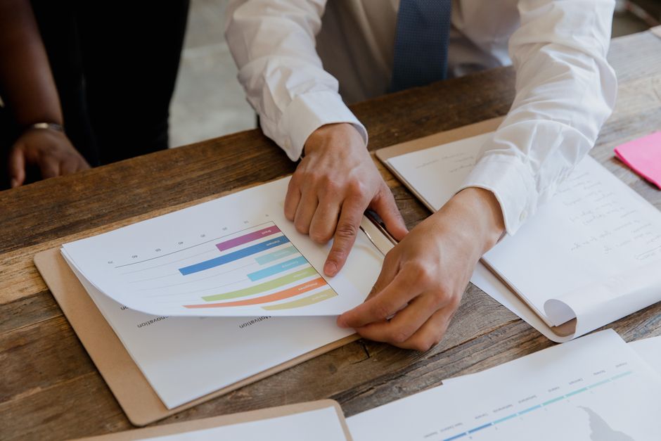An overhead shot of a lawyer's hands pointing to a specific clause in a legal document on a clean desk, advising a client during a consultation.
